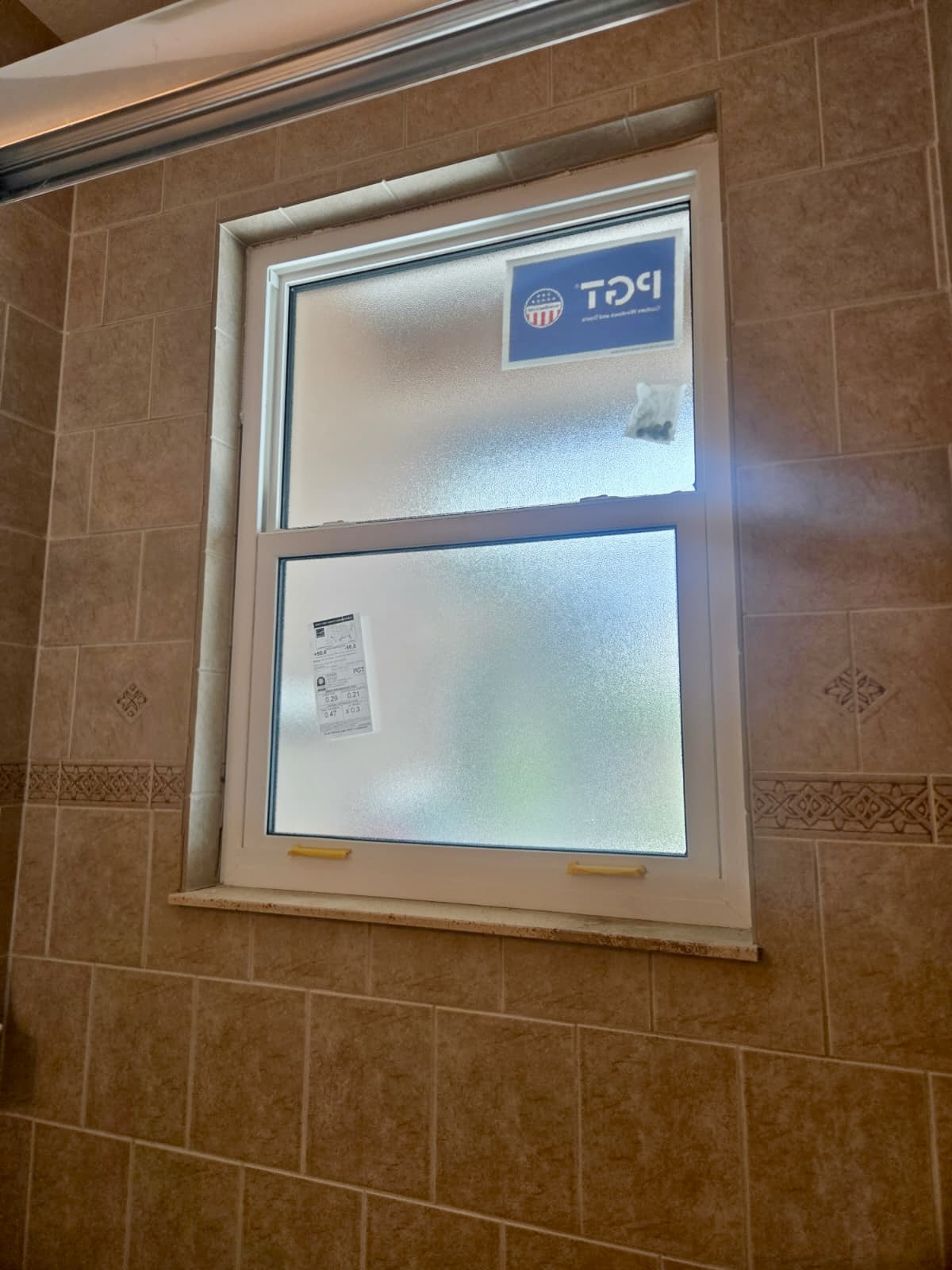 Newly installed PGT hurricane-impact window with obscure glass in a Tampa Bay bathroom