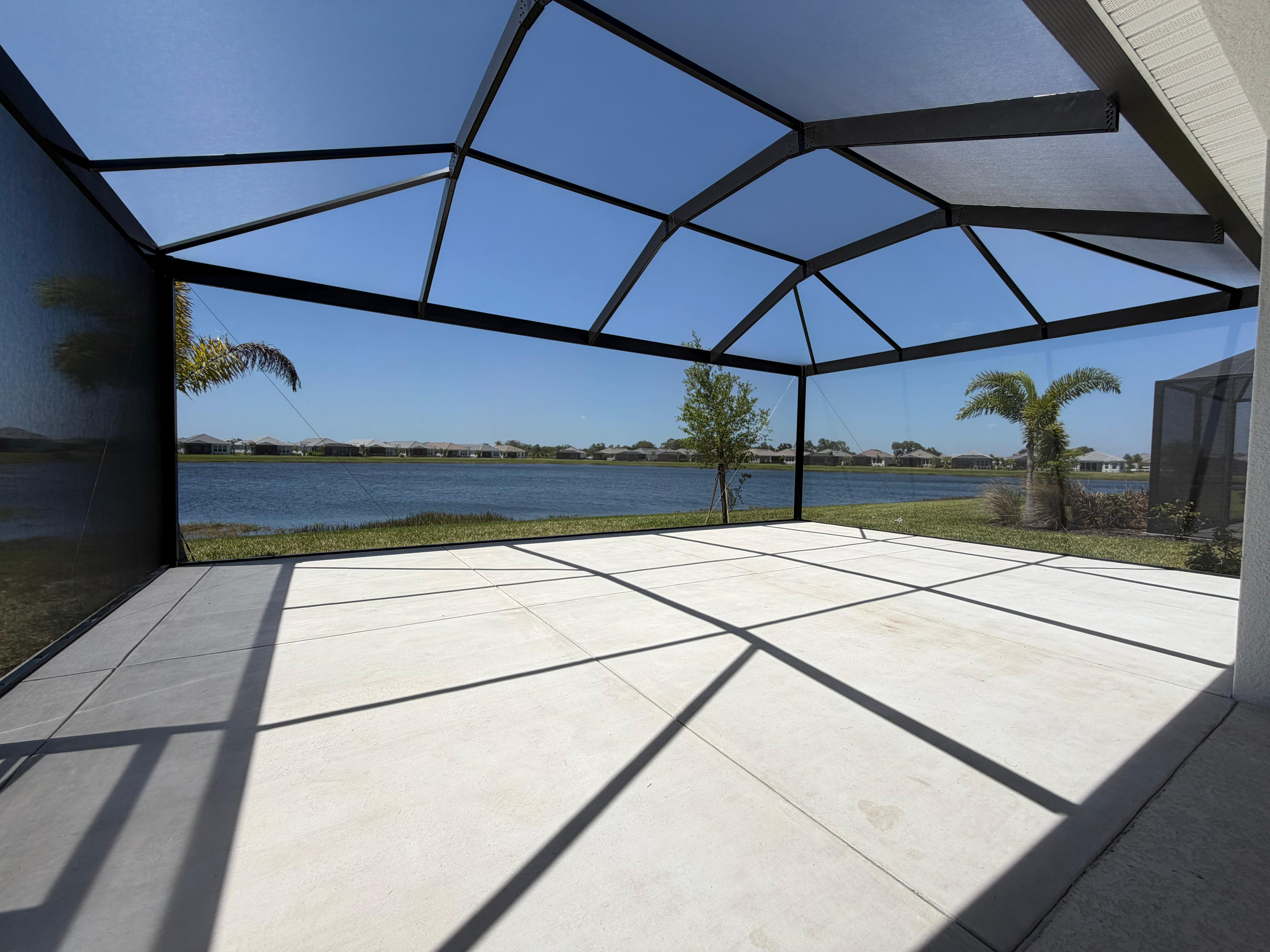 Interior view of a lakefront panoramic bird cage in Parrish, Florida — featuring a mansard roof, 20/20 screen mesh, and oversized aluminum posts. Built by Top Tier Home Building Solutions (#CGC1527718).