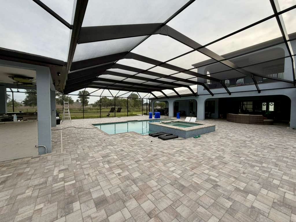 Completed mansard pool enclosure in Brooksville, Florida with pool, spa and herringbone paver deck