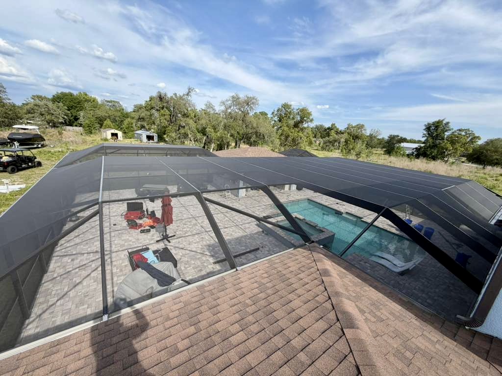 Aerial view of a finished mansard pool cage in Brooksville, FL surrounded by oak trees