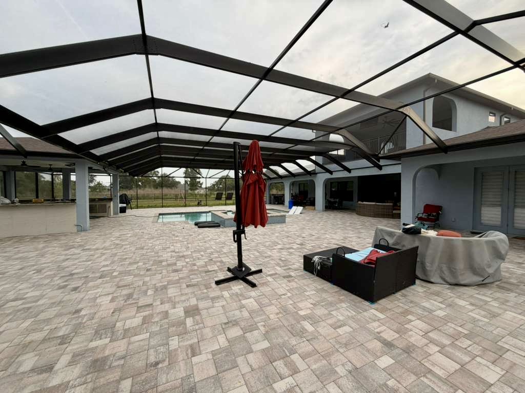 Completed mansard pool cage in Brooksville, FL with interior view of the bronze-black aluminum enclosure over the pool and spa