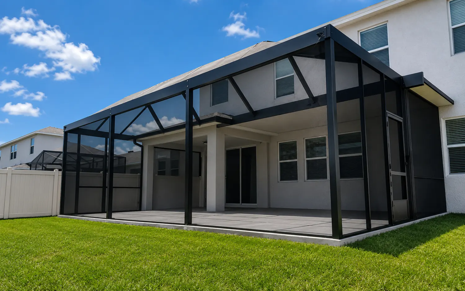 Bird cage screen enclosure with dark aluminum frame and gabled roof over a covered patio on a Florida home