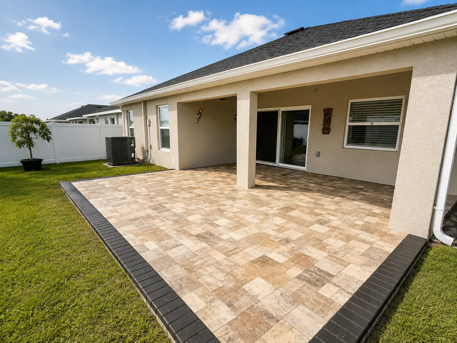 Travertine paver patio with charcoal border installed off a covered lanai on a Florida home
